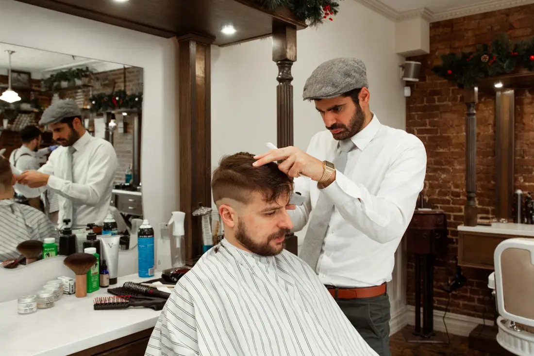 Barbero peinando a un cliente frente al espejo