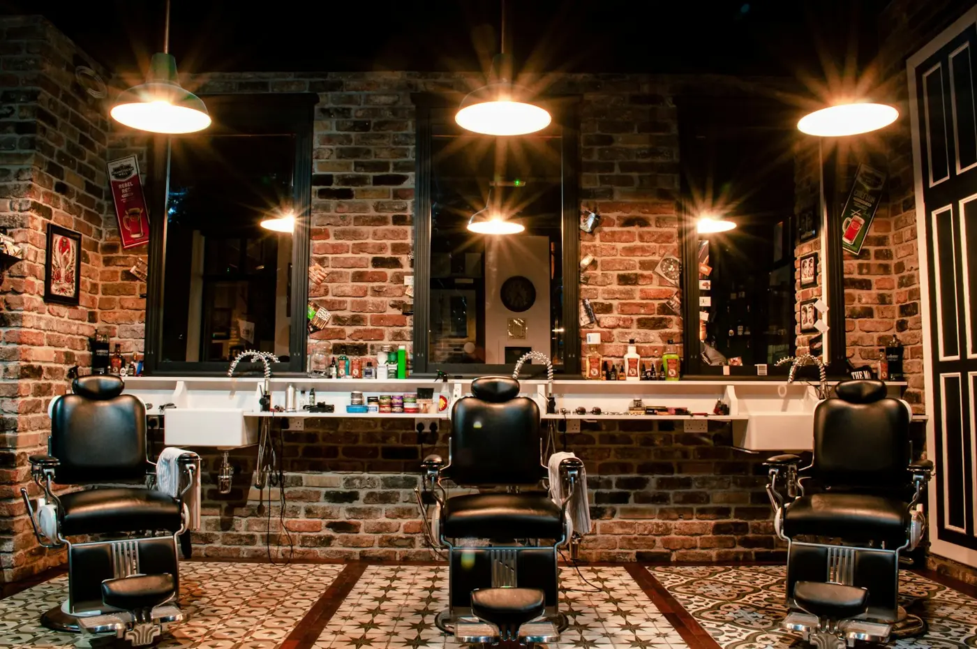 Barbería con tres sillones de piel y muros de ladrillo
